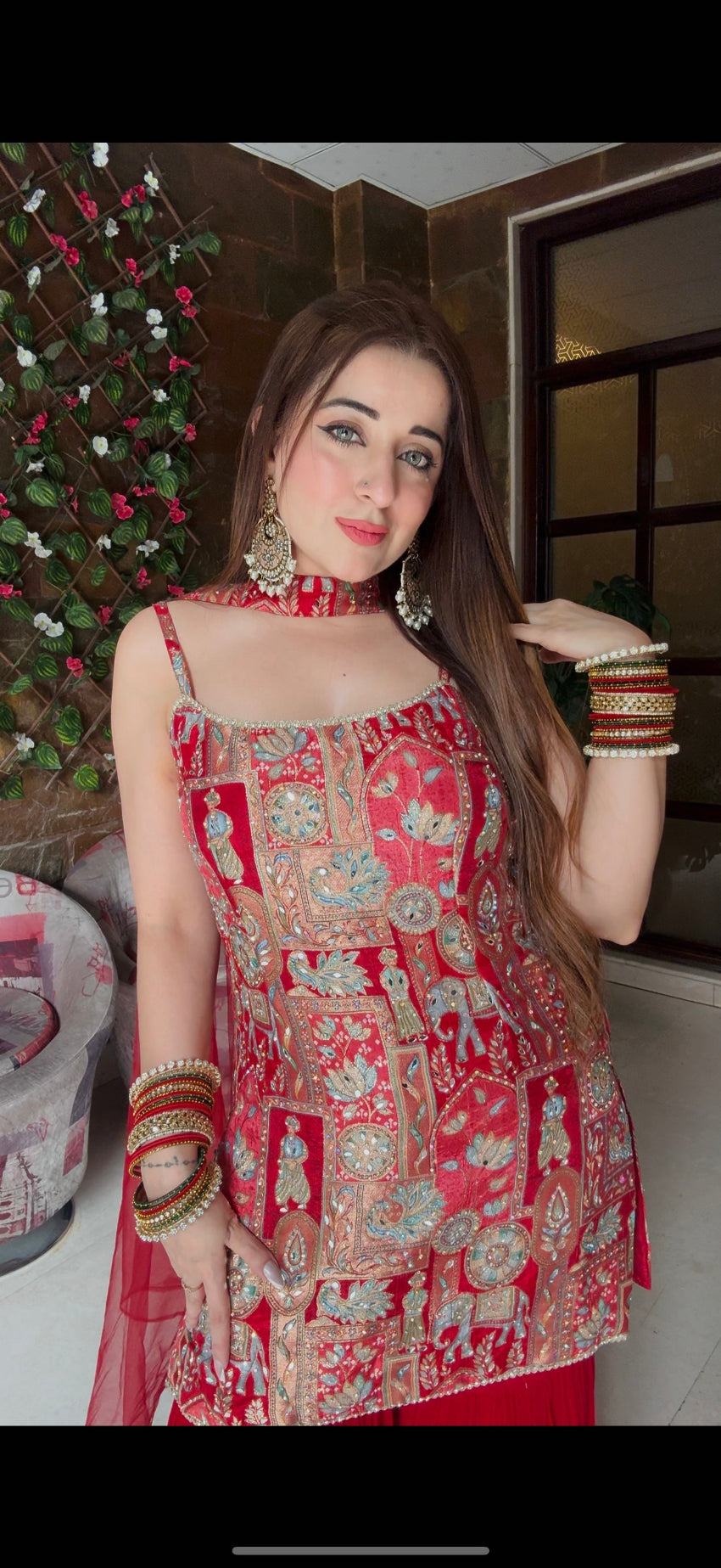 Woman wearing a red and gold traditional outfit with festive background