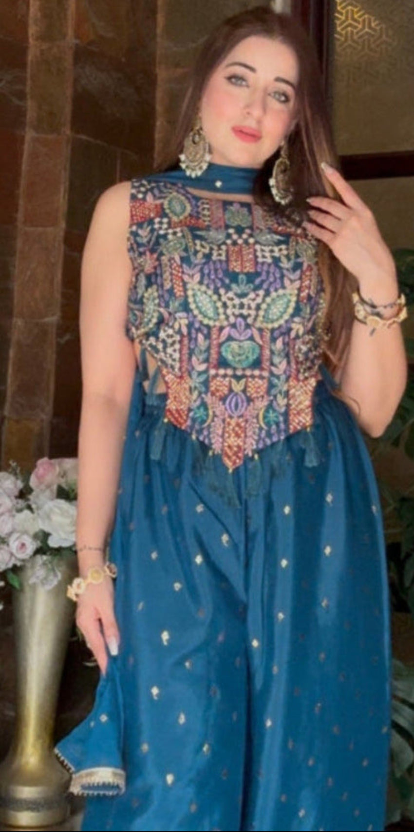 Woman in a blue outfit standing in a room with decorative elements.