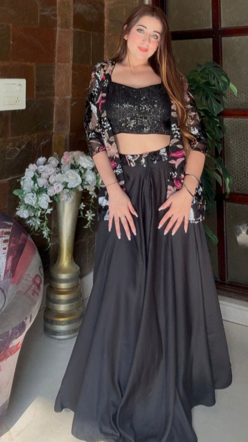 Woman in a black outfit standing in a room with decorative elements.