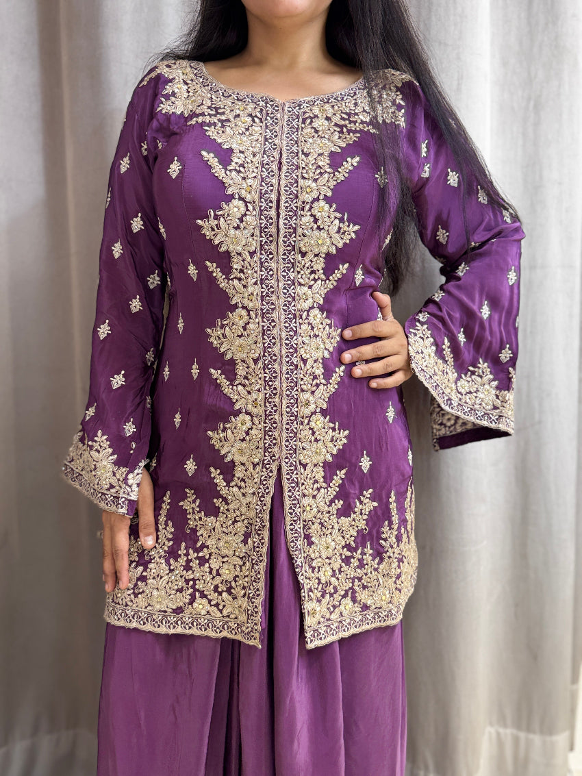Purple traditional outfit with gold embroidery on a plain background