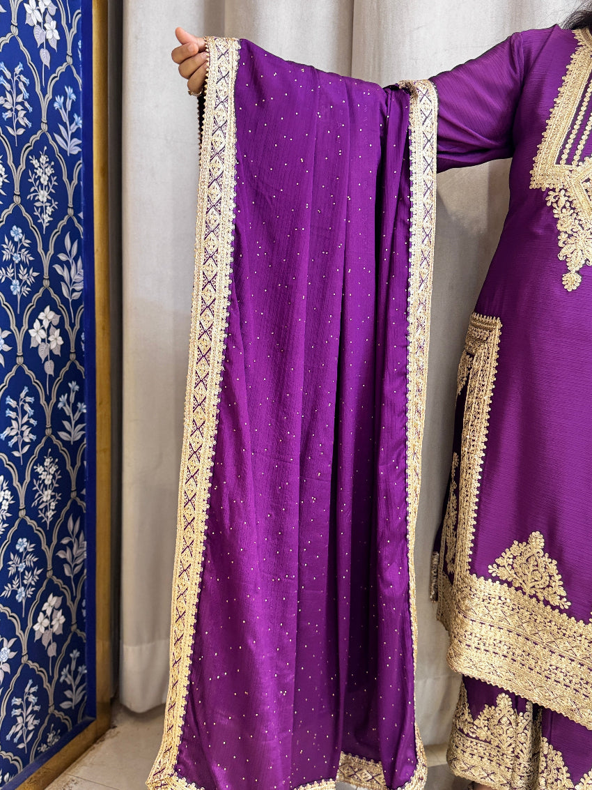 Purple traditional outfit with gold embroidery against a white curtain background