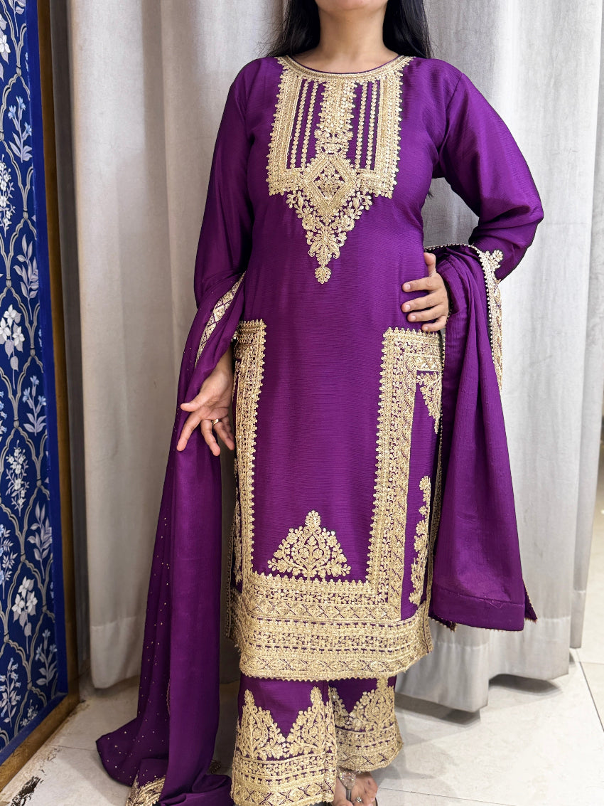 Purple and gold embroidered traditional outfit with a white curtain background