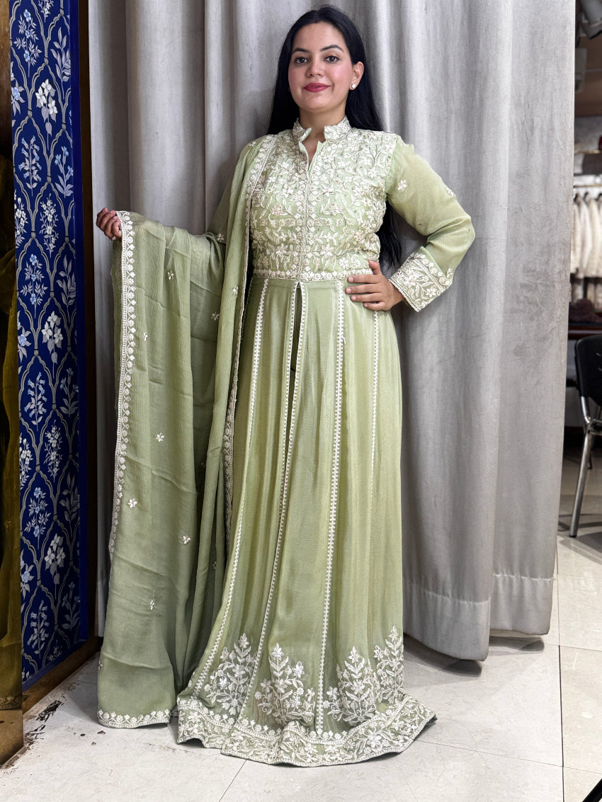 Woman in a light green traditional outfit with white embroidery standing in a store.