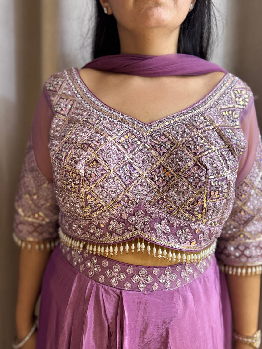 Person wearing a purple embroidered blouse with a matching skirt against a neutral background