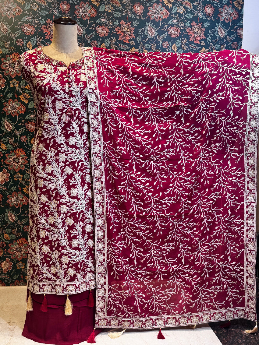 Maroon and white embroidered traditional outfit on a mannequin with a floral patterned background.