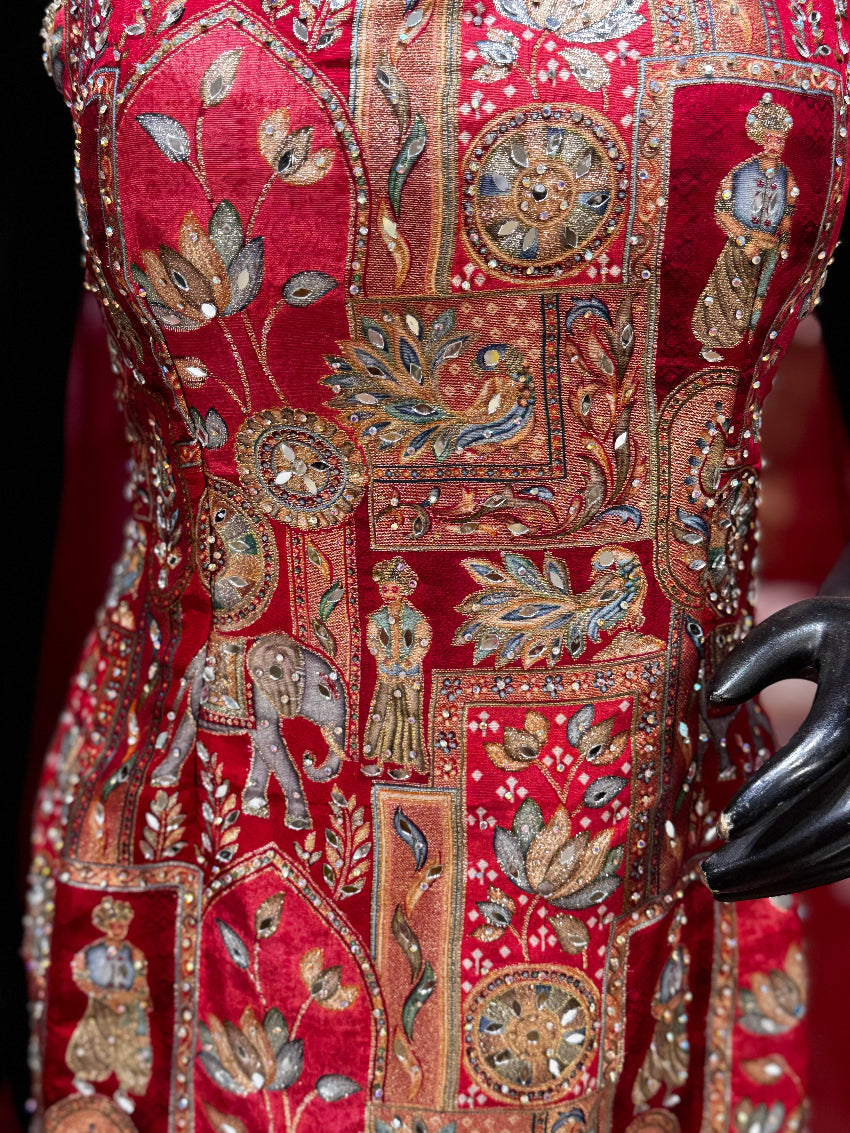Close-up of a red embroidered fabric with intricate patterns and embellishments.