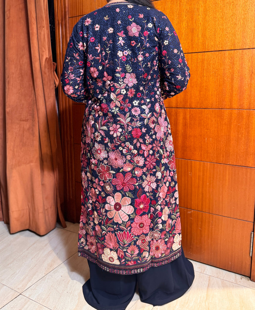 Navy blue kurta with pink floral pattern worn by a person, standing against a wooden door.