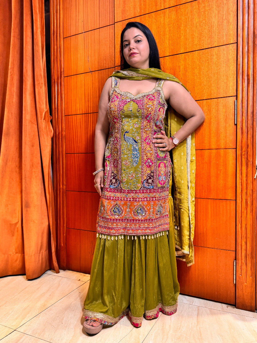 Woman in a colorful traditional outfit standing against an orange wall.
