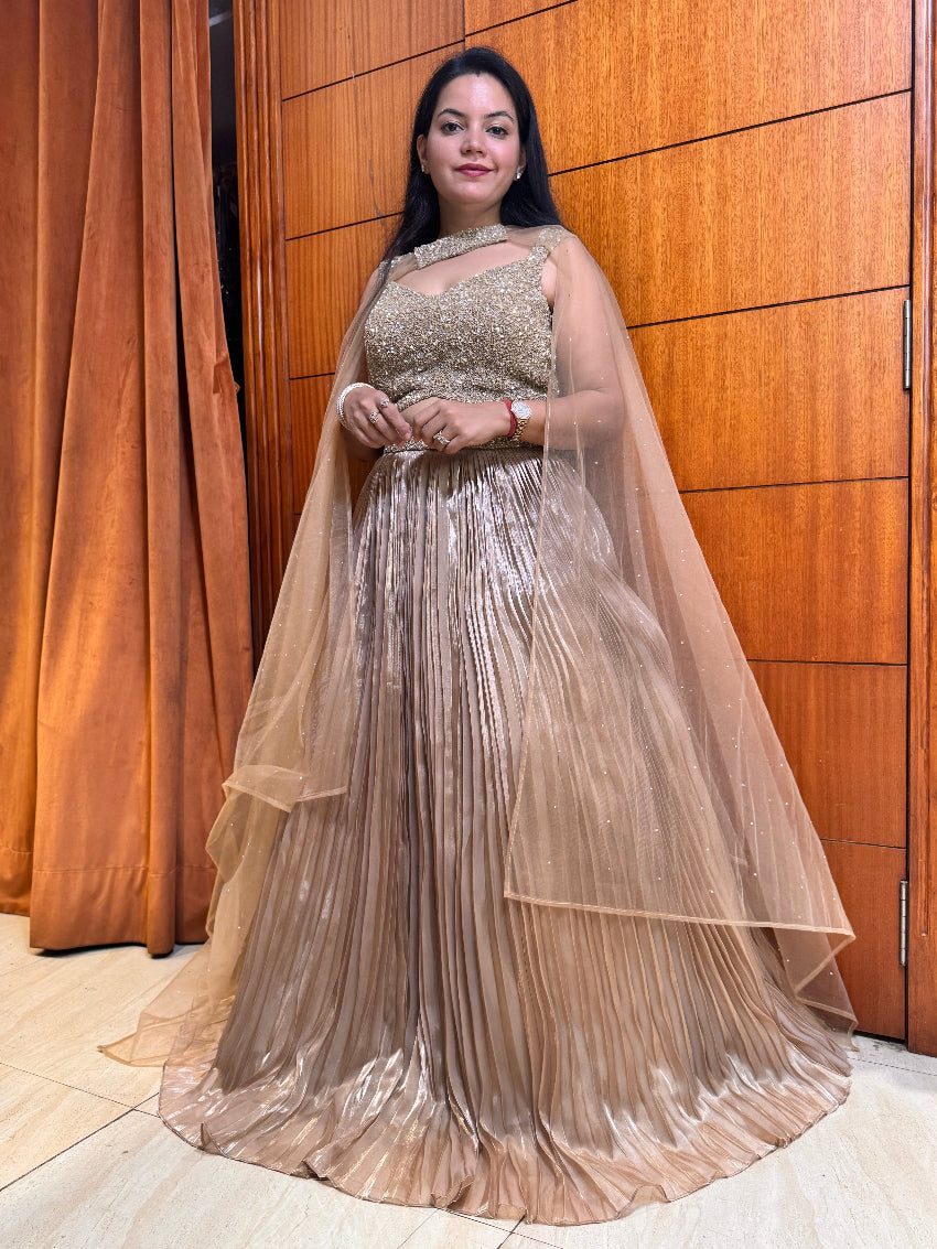 Woman in a sparkling evening gown standing against a wooden paneled wall.