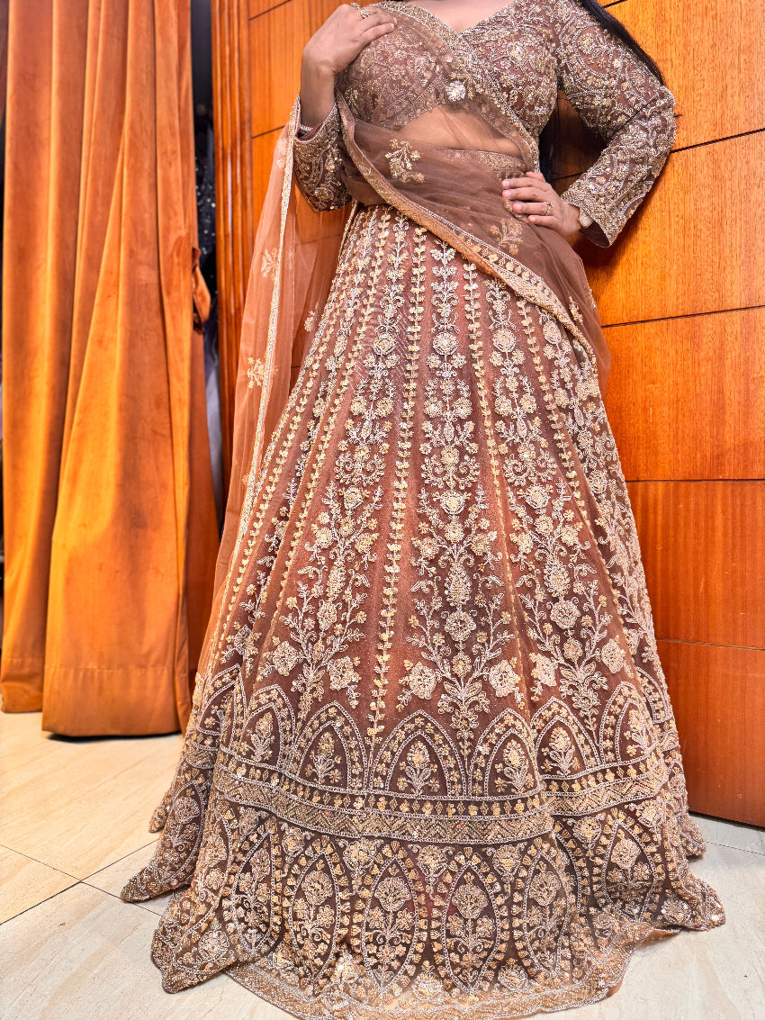 Traditional embroidered outfit with a sheer dupatta against a wooden background
