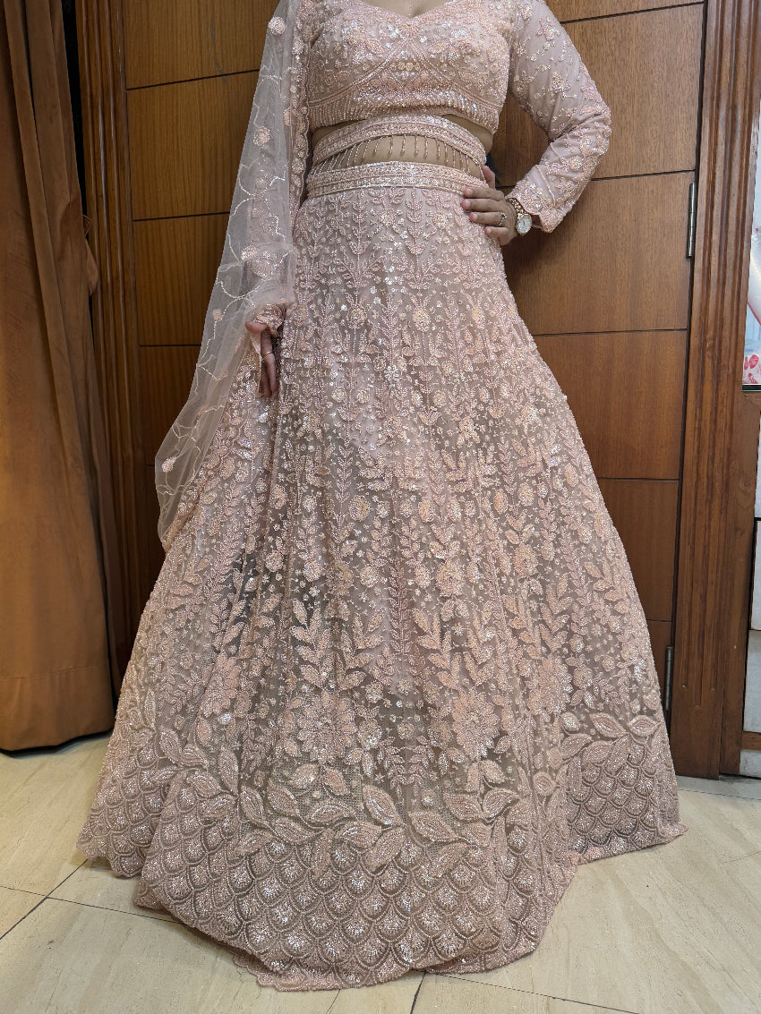 Beige embroidered traditional outfit with a long skirt and top on a wooden floor.