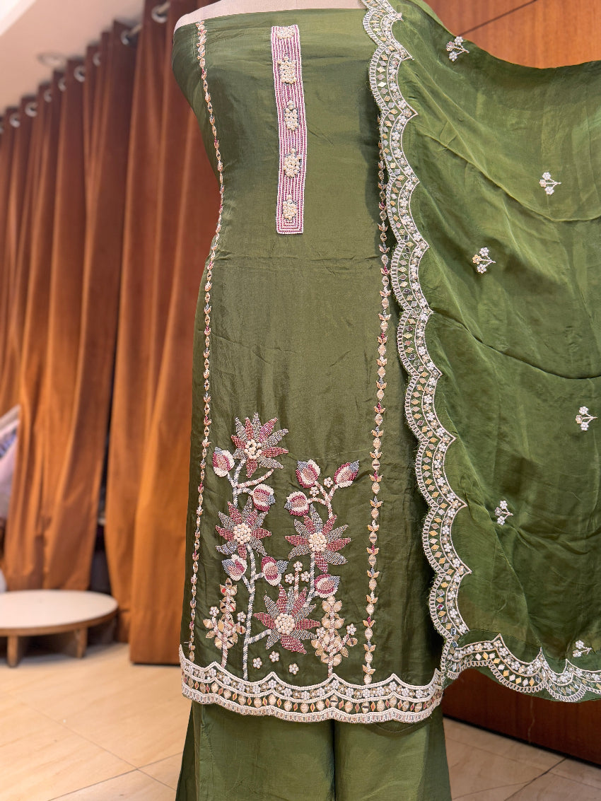 Green embroidered dress on a mannequin with a brown curtain background