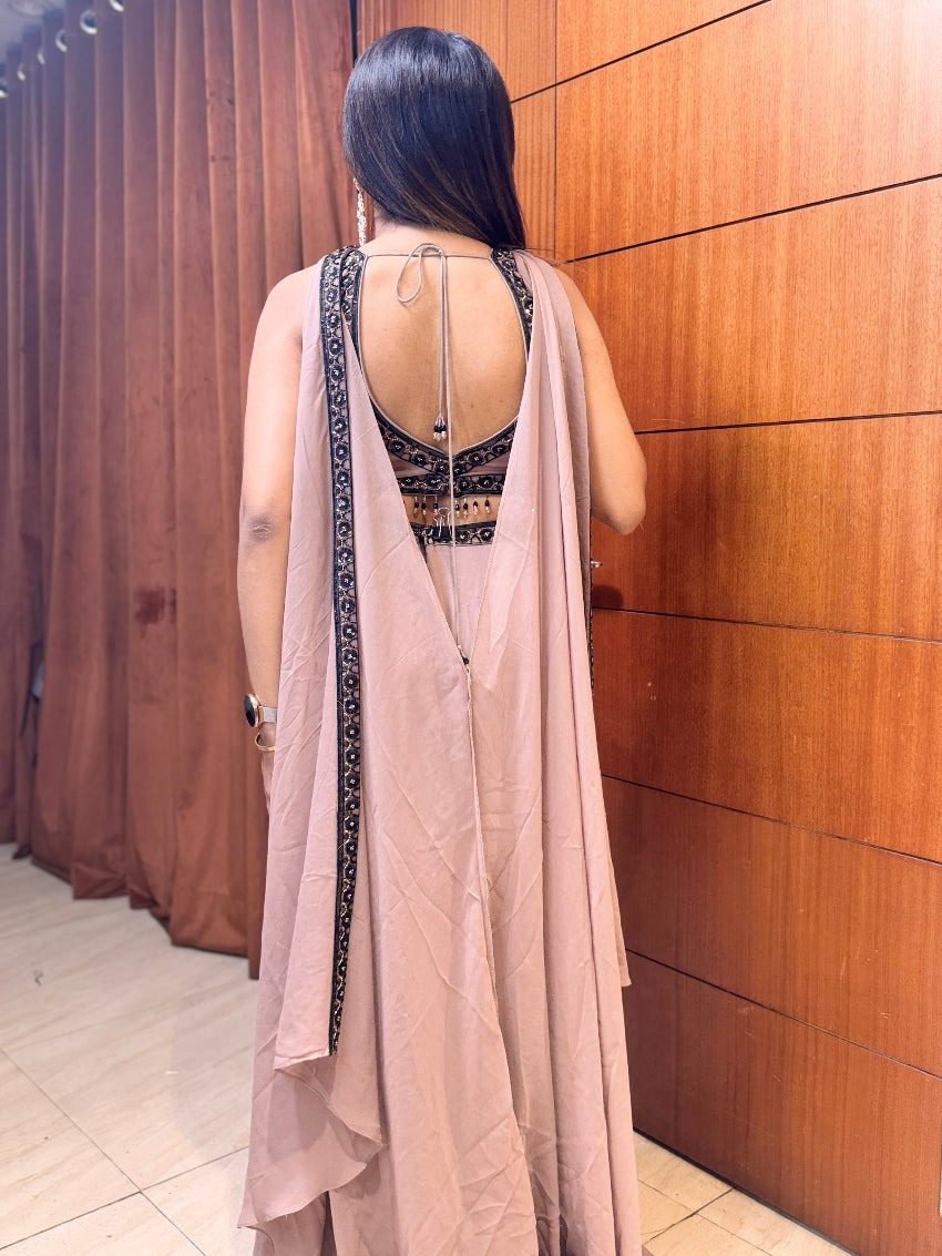 Woman wearing a long, light-colored dress with a backless top against a wooden panel wall.