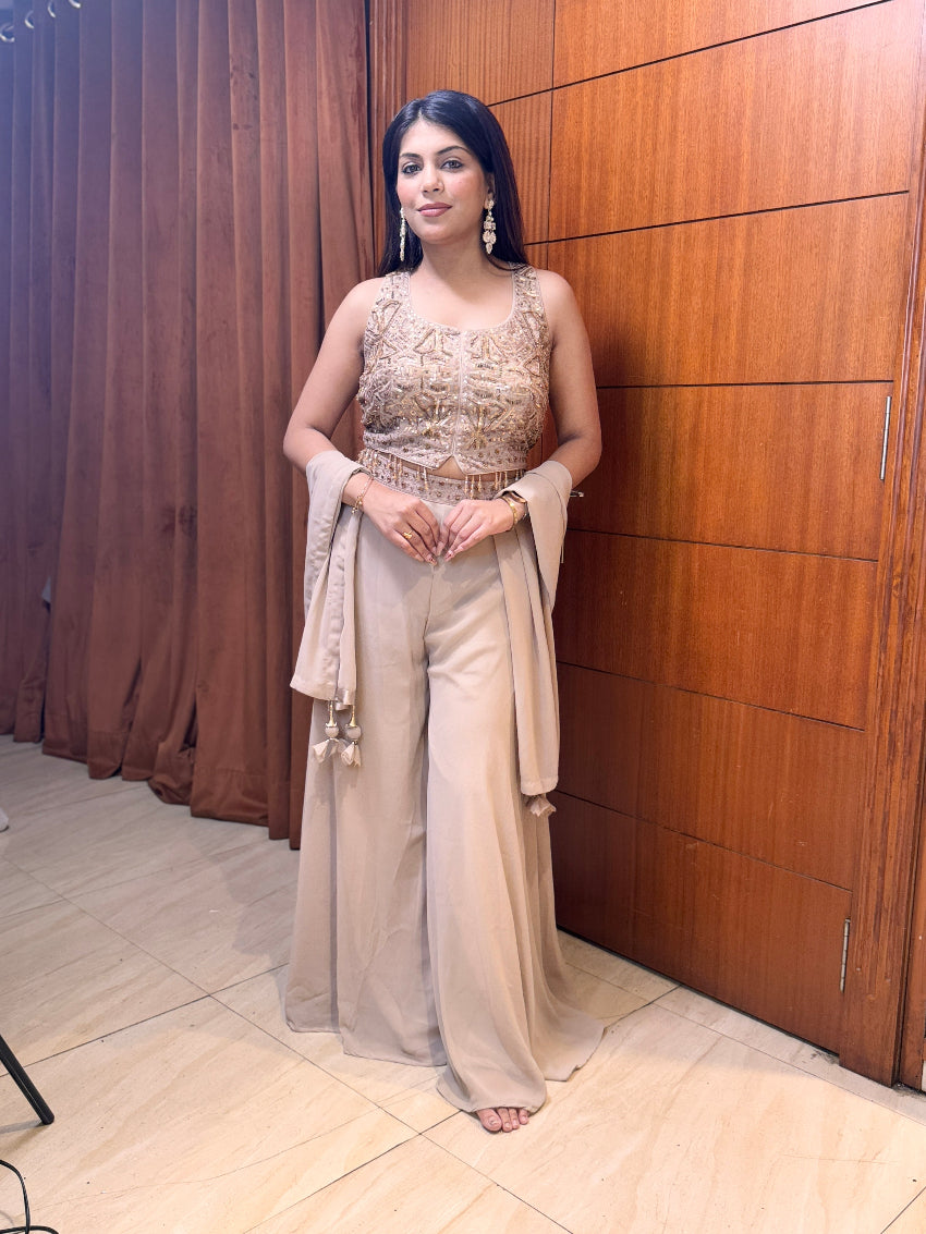 Woman in a formal outfit standing against a wooden paneled wall.