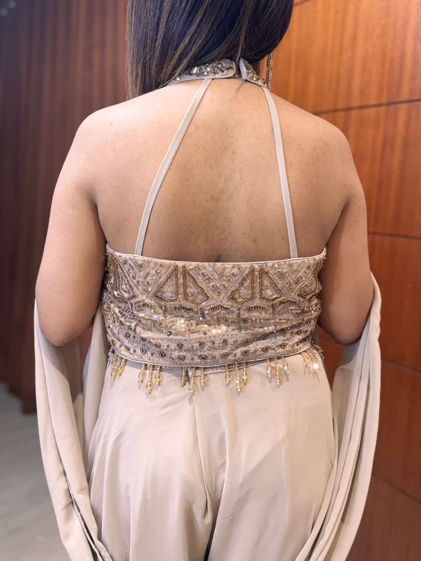 Back view of a person wearing an elegant beige dress with intricate detailing.