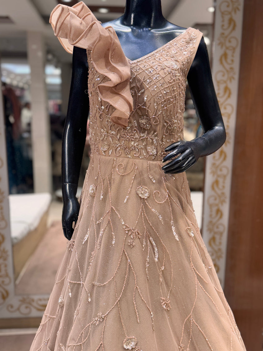 Beige evening gown with intricate detailing on a mannequin in a store setting.