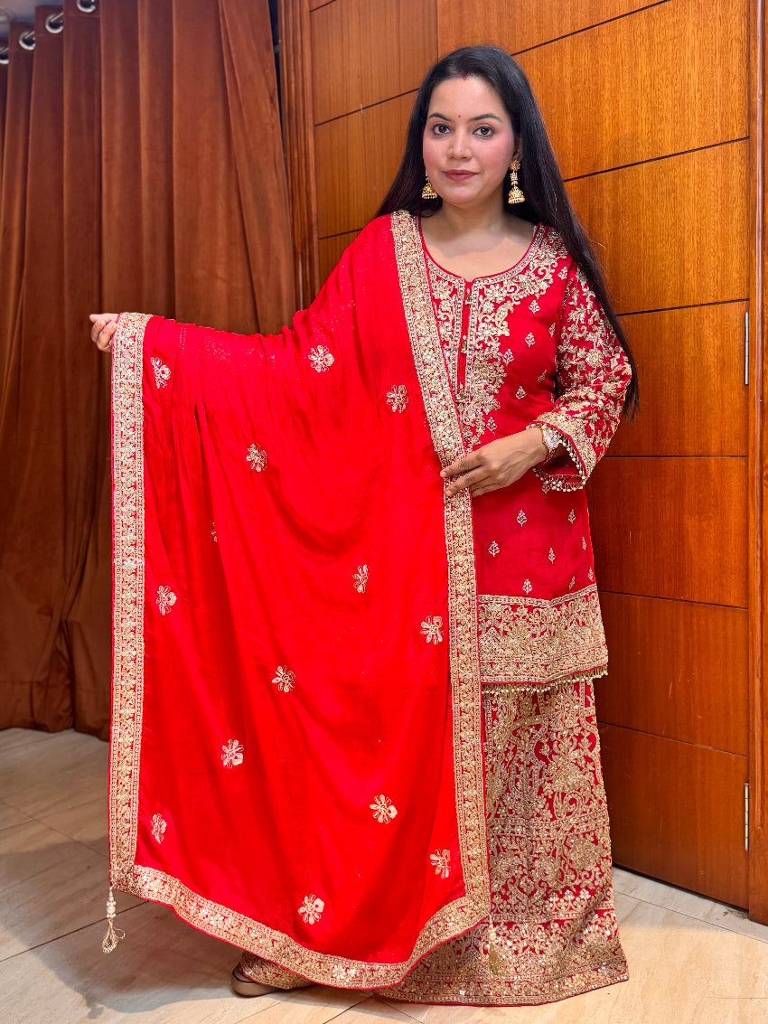 Woman wearing a red and gold embroidered traditional outfit against a wooden panel background