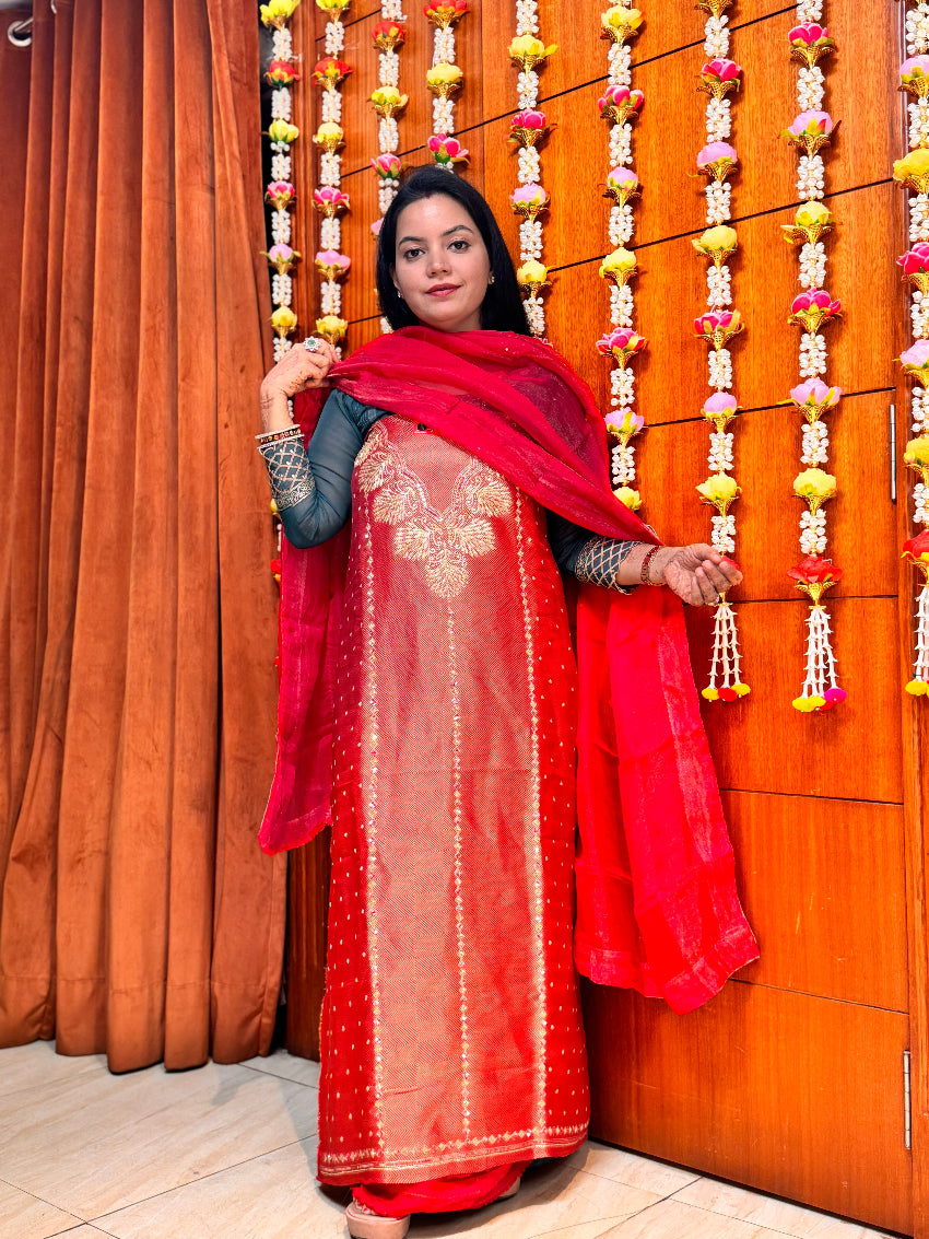 Woman in traditional outfit standing in front of a decorated wooden door.