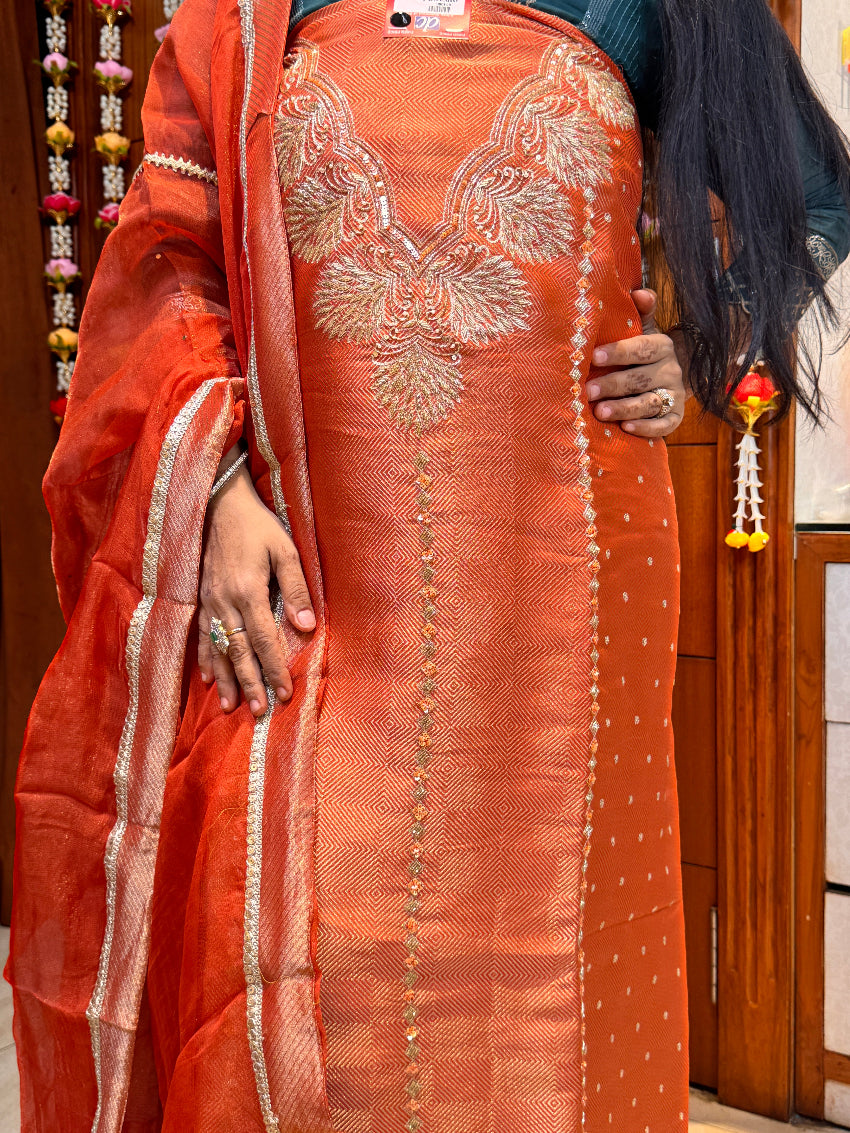 Person holding a traditional orange saree with intricate patterns