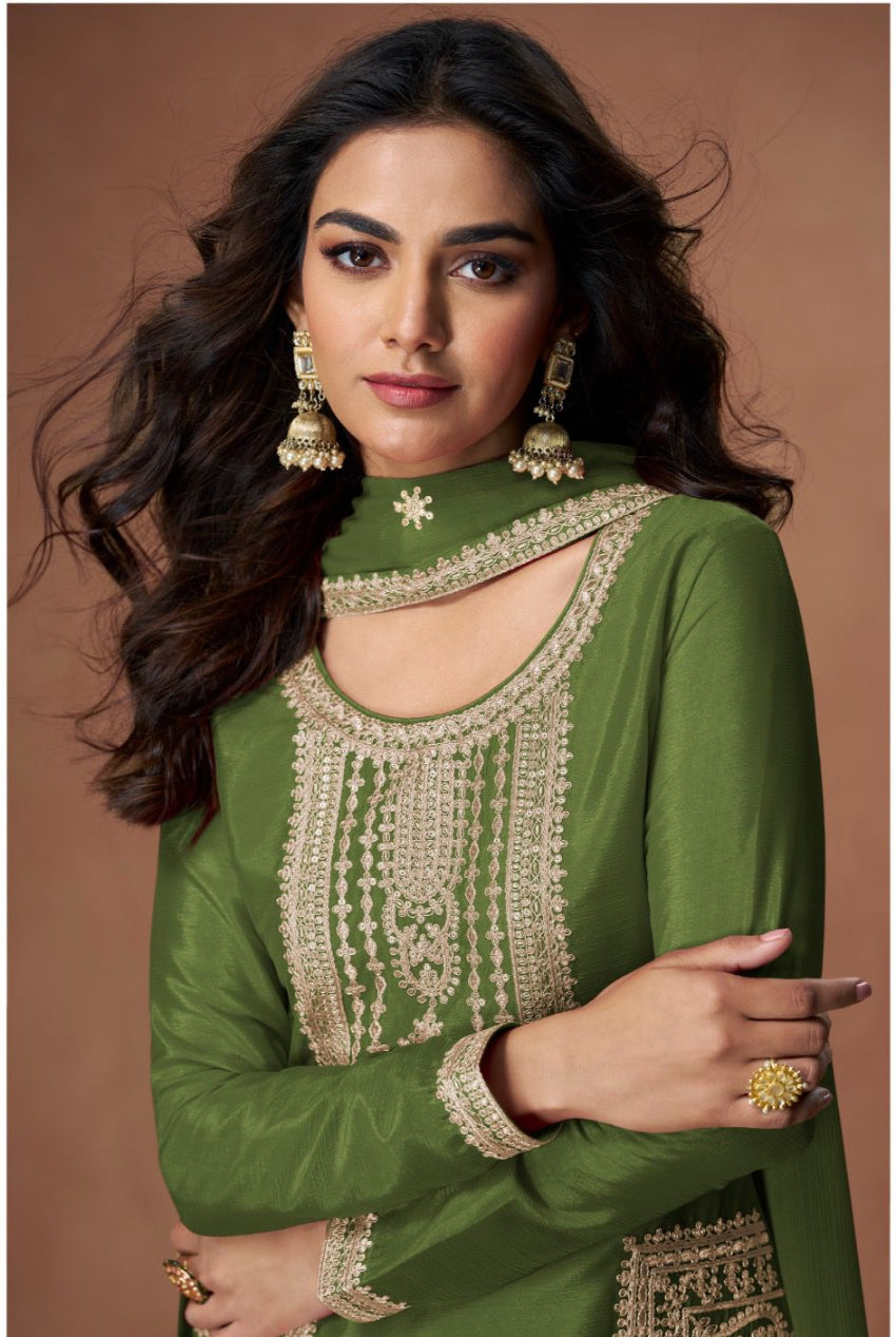 Woman wearing a green embroidered traditional outfit against a brown background