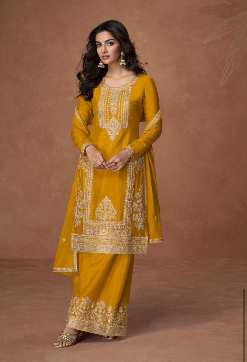 Woman wearing a mustard yellow embroidered traditional outfit on a brown background