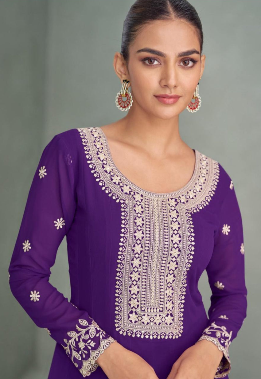 Woman wearing a purple embroidered outfit against a gray background