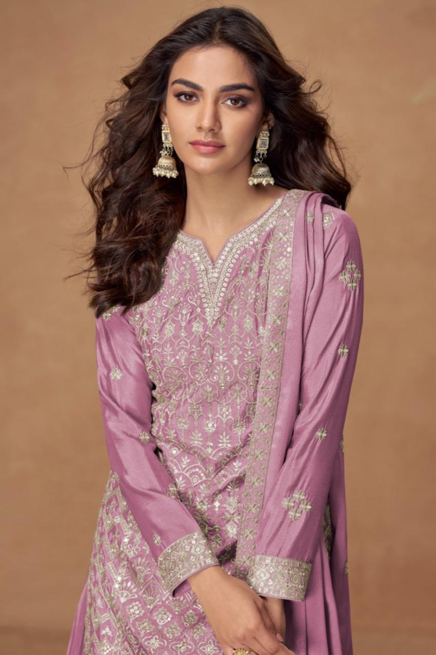 Woman wearing a purple traditional outfit with intricate patterns on a brown background