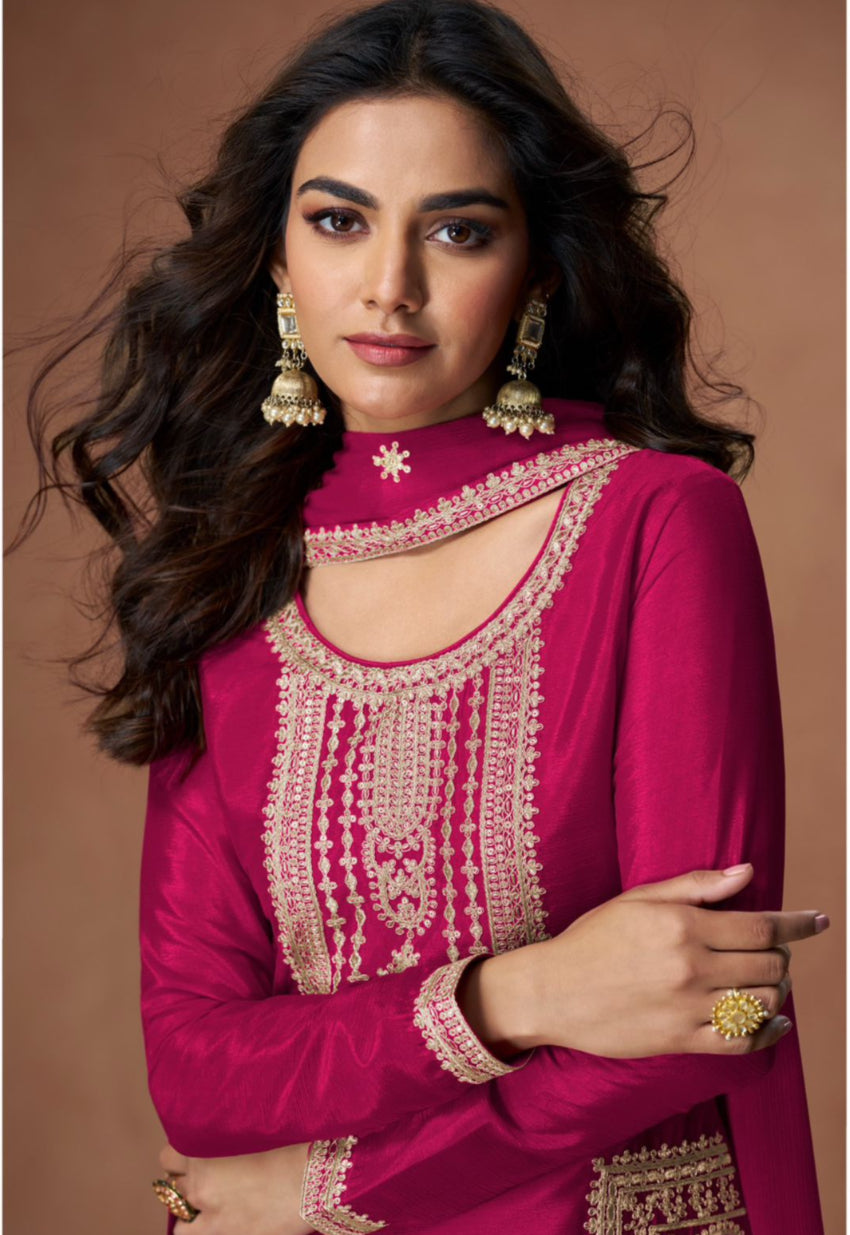 Woman wearing a pink traditional outfit with intricate designs on a brown background