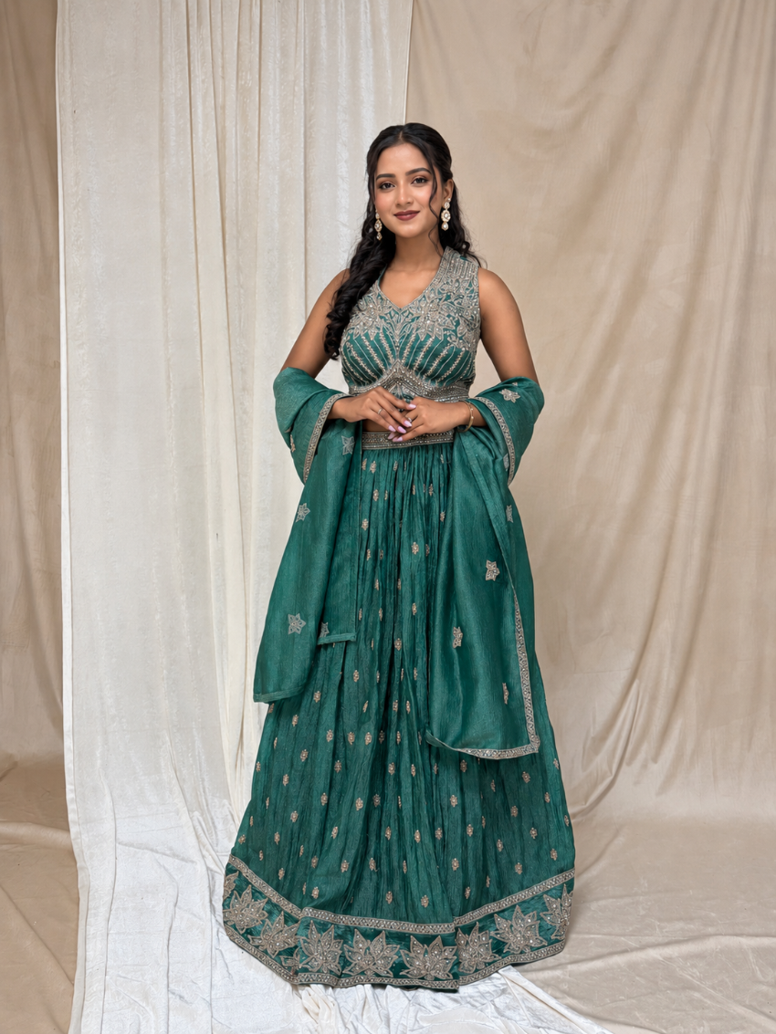 Woman in a green traditional outfit with silver details against a beige curtain background