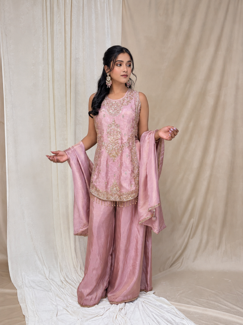 Woman in a pink traditional outfit with embroidery against a beige curtain background