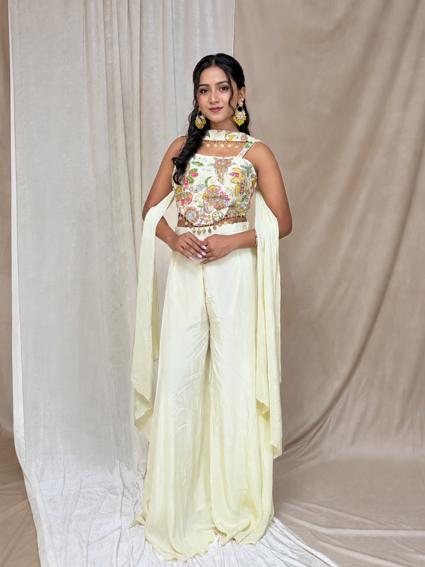 Woman wearing a traditional outfit with a floral top and light yellow saree against a plain background