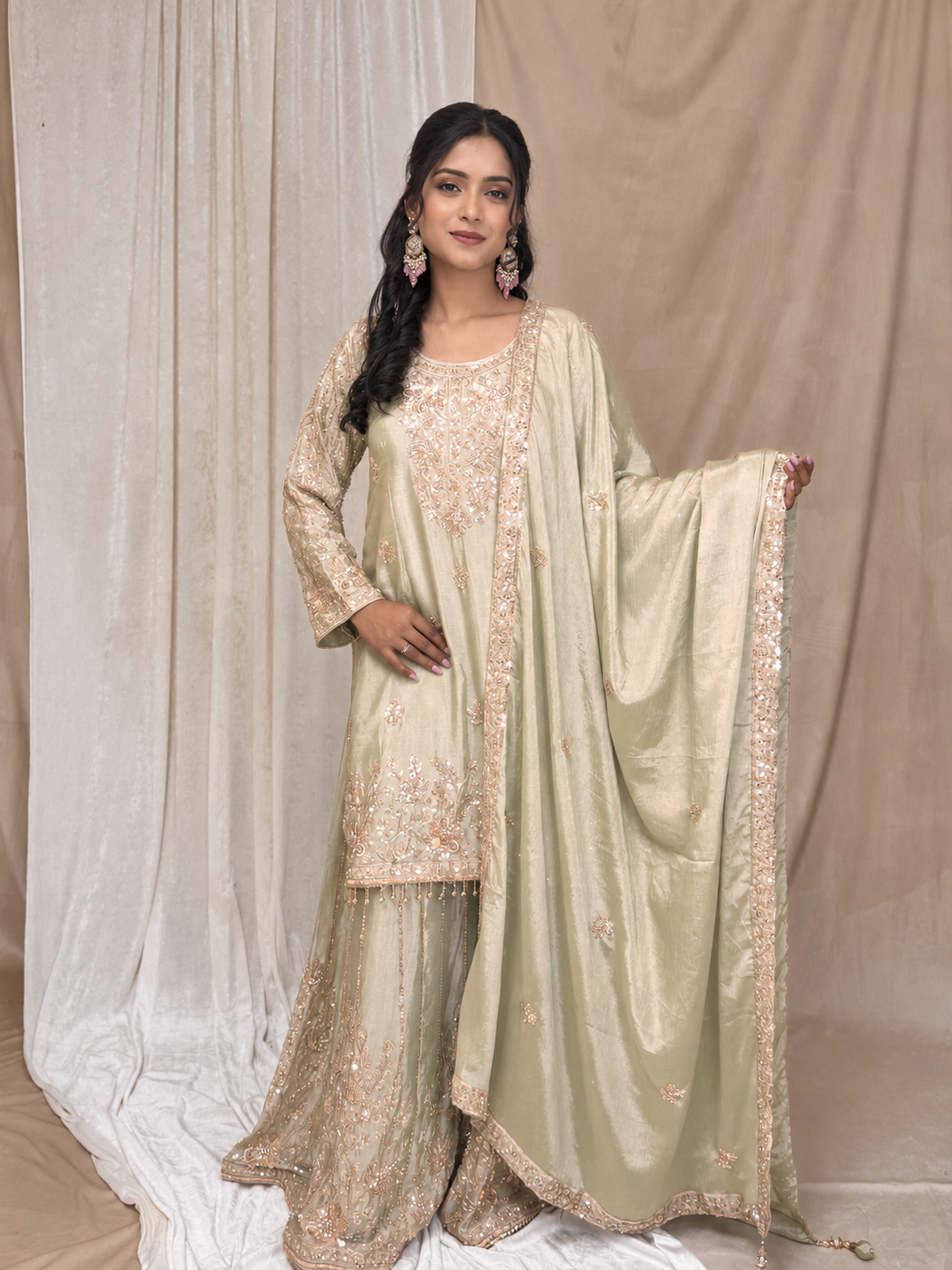 Woman wearing a traditional outfit with intricate designs against a neutral background
