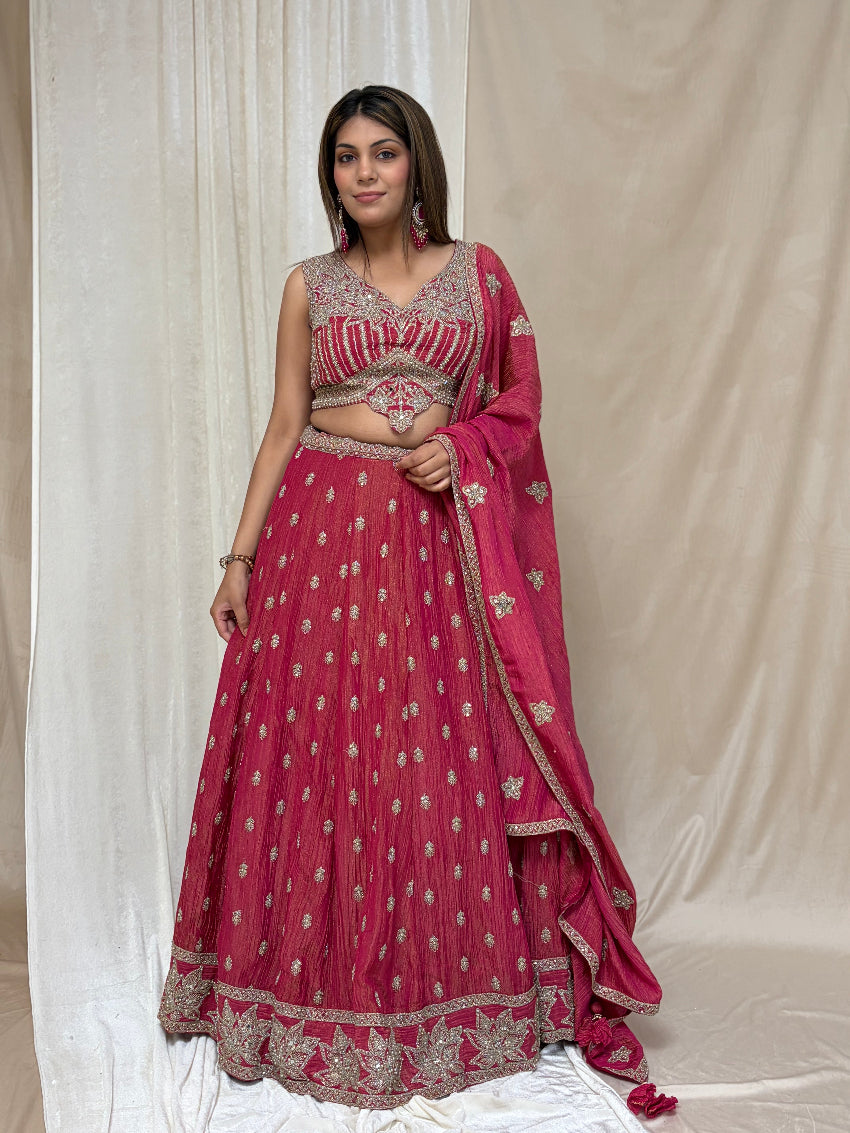 Woman wearing a traditional pink and silver lehenga with a plain background