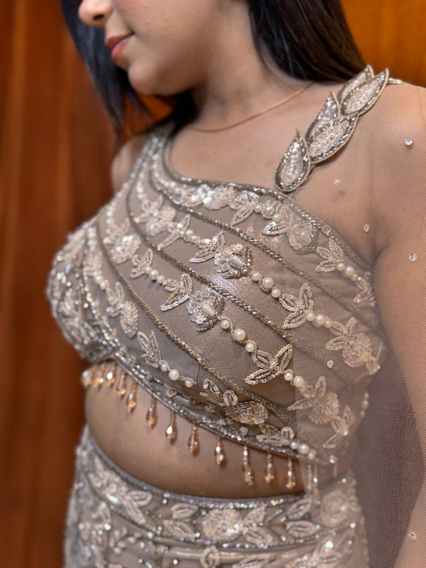 Silver embroidered blouse with intricate designs on a plain background
