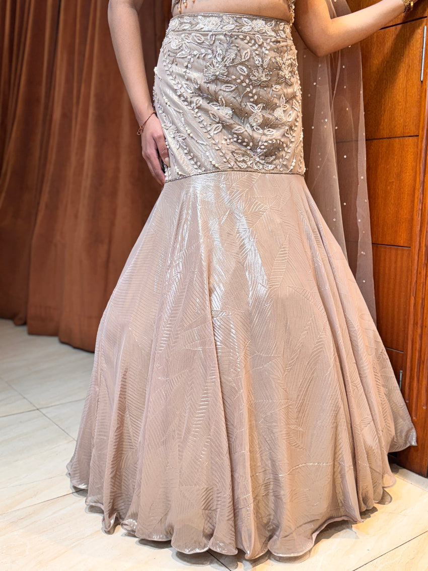 Beige evening gown with intricate detailing on a neutral background