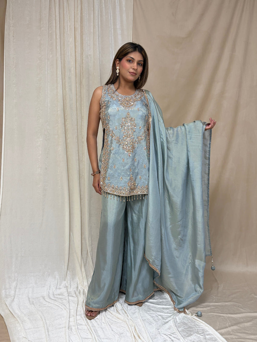 Woman wearing a light blue traditional outfit with a dupatta against a neutral background