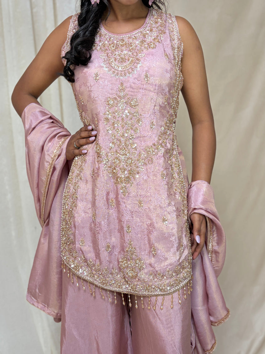 Woman wearing a pink embroidered traditional outfit with a matching dupatta against a plain background