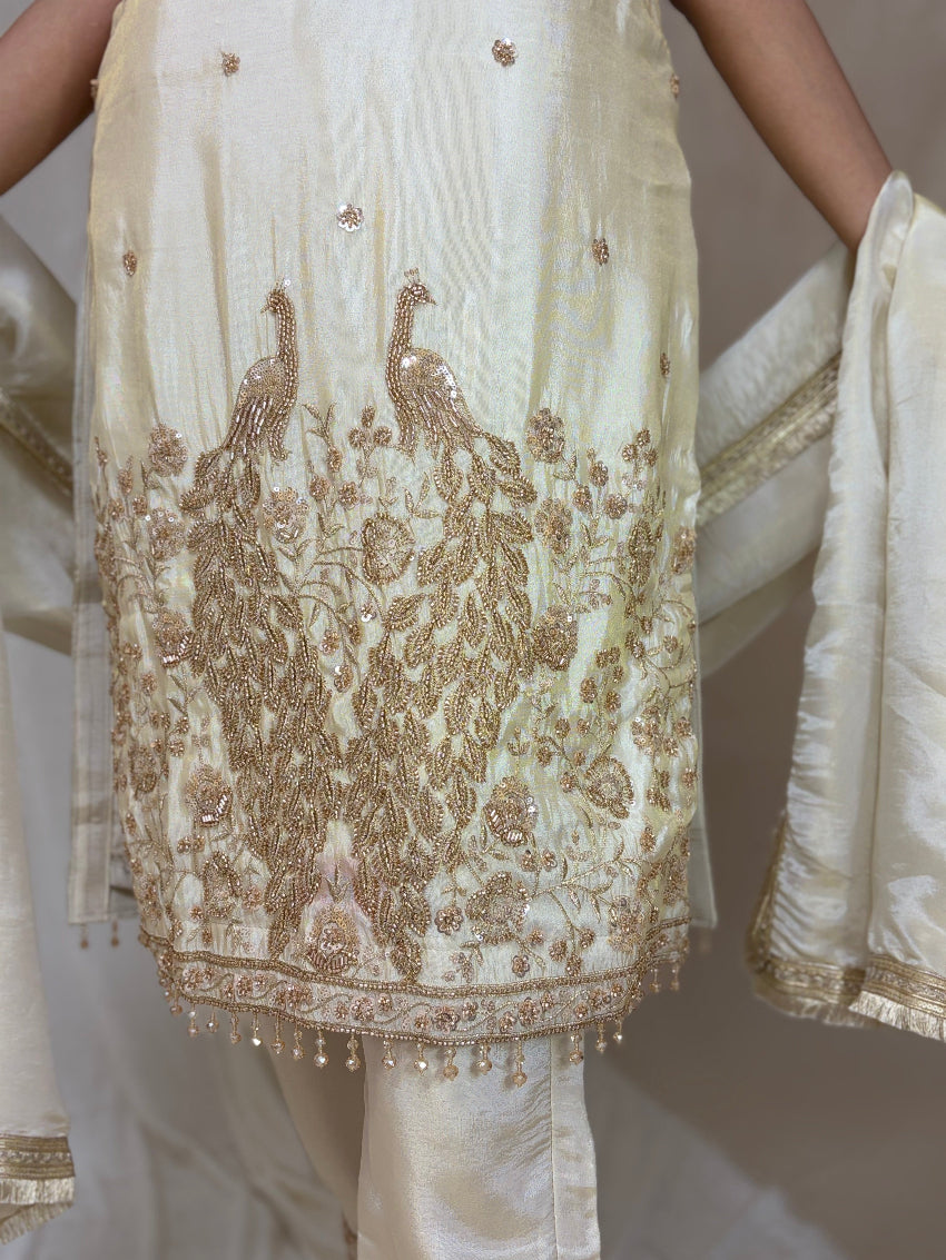 White embroidered traditional outfit with gold details on a neutral background