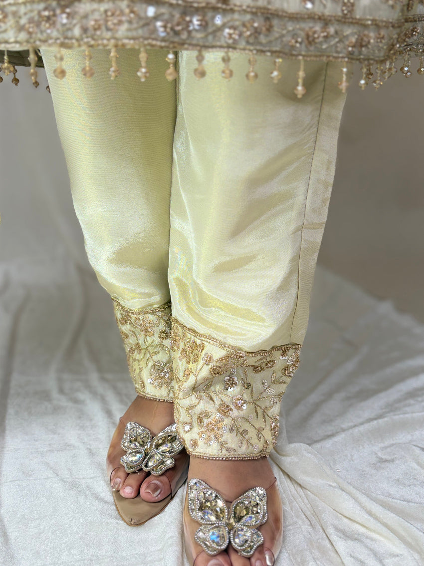 Light-colored traditional outfit with intricate embroidery and embellishments on a white fabric background