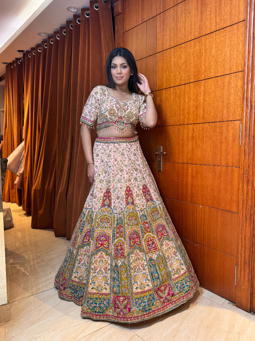 Woman in a traditional embroidered outfit standing in front of a wooden door.