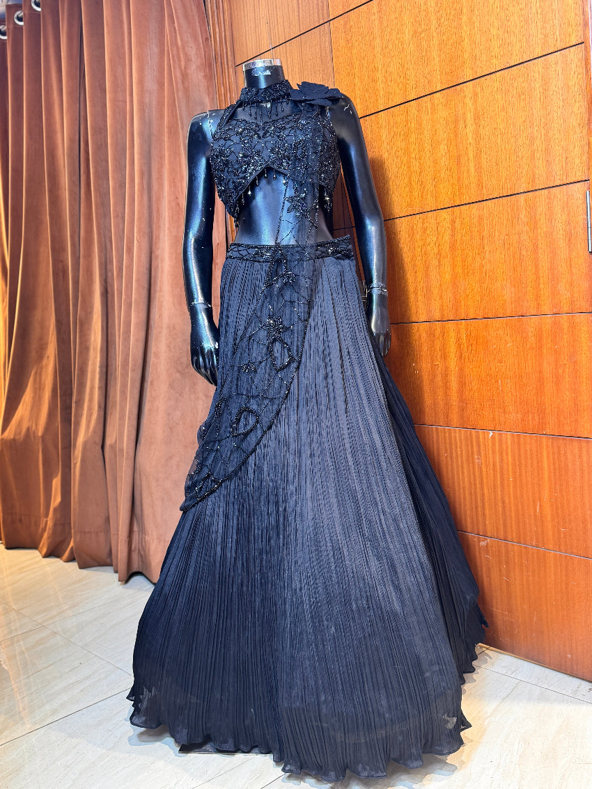 Black evening gown on a mannequin against a wooden paneled wall.