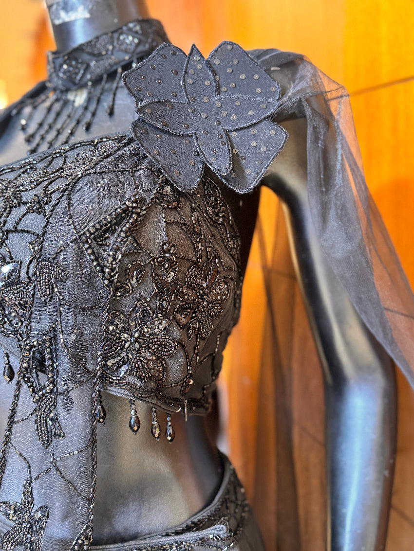 Close-up of a black embroidered garment with floral details on a mannequin.