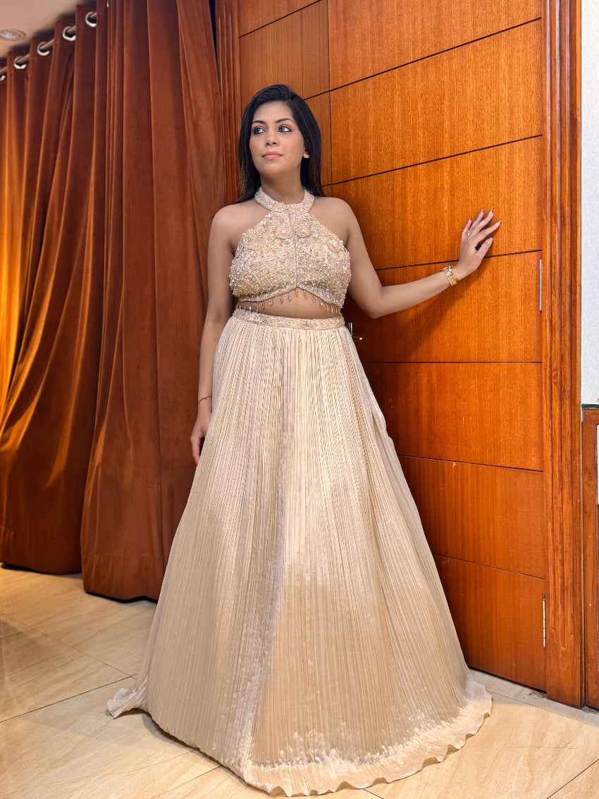 Woman in a beige dress standing against a wooden wall.