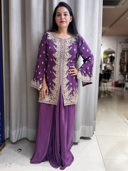 Woman wearing a purple traditional outfit with intricate designs indoors.