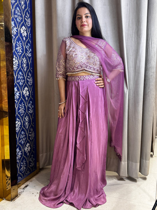 Woman wearing a purple saree with a matching blouse in a room.
