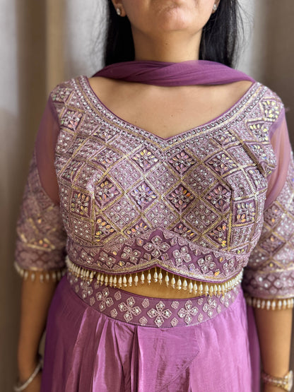 Person wearing a purple embroidered blouse with a matching skirt against a neutral background