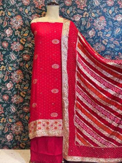 Red fabric with intricate patterns on a mannequin against a floral wallpaper background