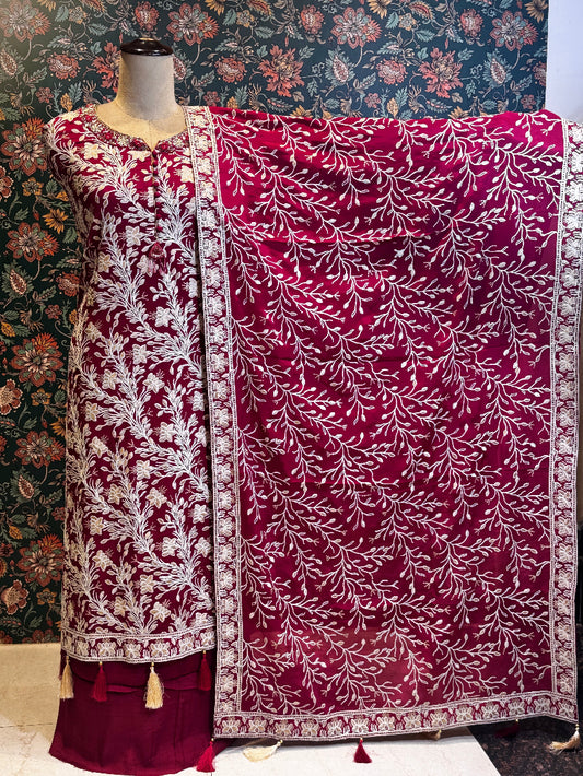 Maroon and white embroidered traditional outfit on a mannequin with a floral patterned background.