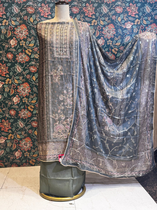Mannequin draped with patterned fabric against a floral wallpapered wall