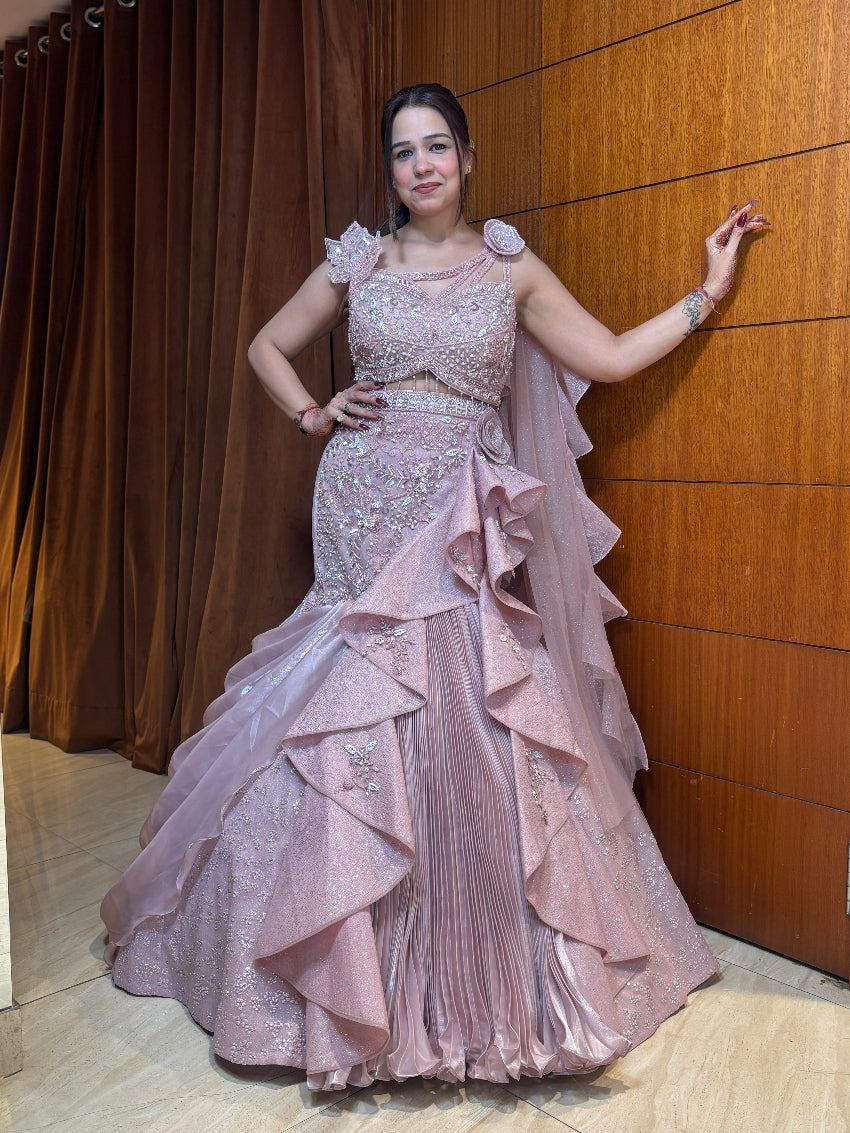 Woman in a pink evening gown posing against a wooden panel wall.